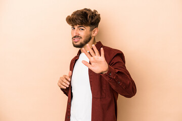 Young arab man isolated on beige background being shocked due to an imminent danger