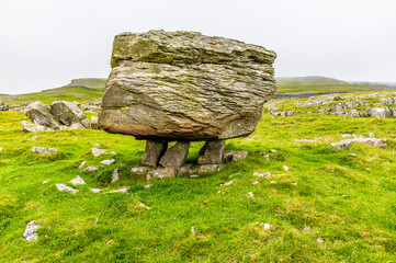 A view showing a glacial erratic supported on the limestone pavement on the southern slopes of Ingleborough, Yorkshire, UK in summertime
