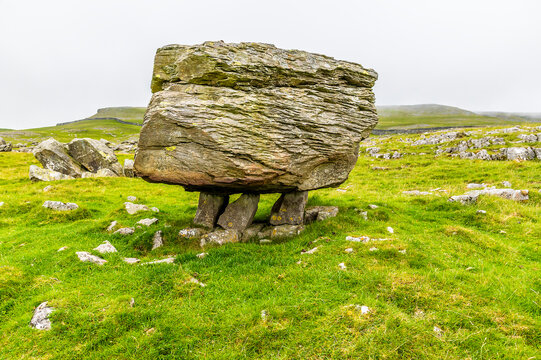A view showing a glacial erratic supported on the limestone pavement on the southern slopes of Ingleborough, Yorkshire, UK in summertime