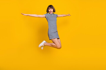 Full length photo of cool brunette young lady jump wear dress sneakers isolated on yellow background