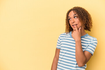 Young latin transsexual woman isolated on yellow background relaxed thinking about something looking at a copy space.