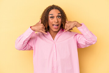 Young latin transsexual woman isolated on yellow background showing a mobile phone call gesture with fingers.