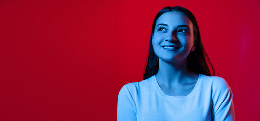 Cropped portrait of young beautiful woman in white T-shirt posing isolated over red background in...