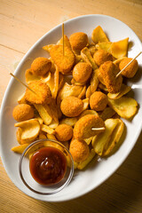 dish with mixed fried, stuffed olives, potato croquettes, fried potato dippers and sauce. over...