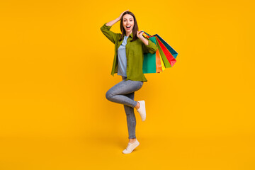 Photo of impressed pretty young lady wear green shirt smiling holding shopping bags arm head...