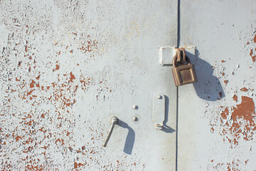 Rusty metal gate with a lock, painted in gray paint