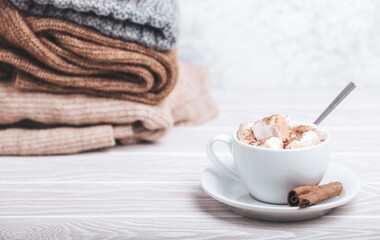 Cozy winter composition, cup with hot chocolate or cocoa with marshmallow and pile of warm knitted...