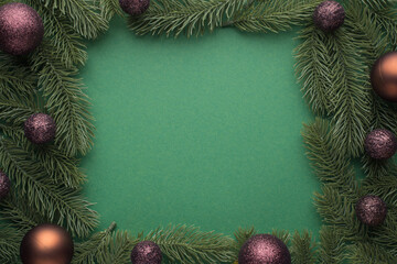 Fototapeta na wymiar Top view photo of brown and gold christmas tree balls on pine branches on isolated green background with empty space in the middle