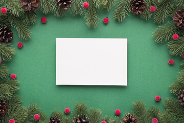 Fototapeta na wymiar Top view photo of paper sheet christmas decorations pine branches with cones and red berries on isolated green background with empty space