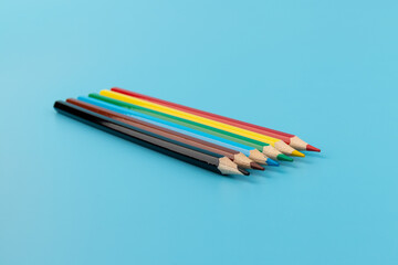 Six colored pencils close-up on a blue background with a copy of the space. The texture of bright colored wooden pencils.