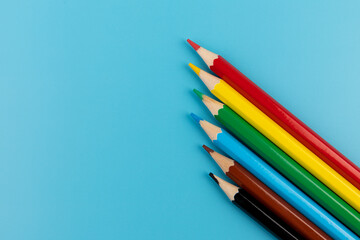 Six colored pencils close-up on a blue background with a copy of the space. The texture of bright colored wooden pencils.