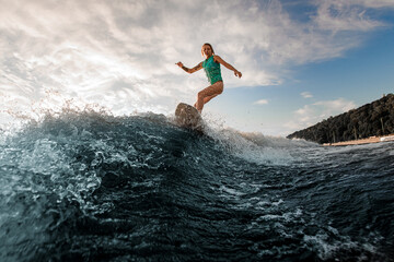 beautiful view of the wave and a young athletic woman on a wakeboard