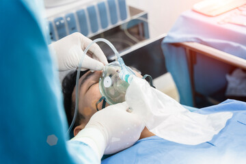assistant surgeon put the patient on a ventilator-oxygen mask in preparation for surgery. - Powered by Adobe