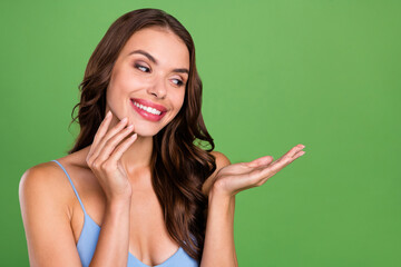 Photo of young woman happy positive smile look recommend product offer skincare isolated over green color background