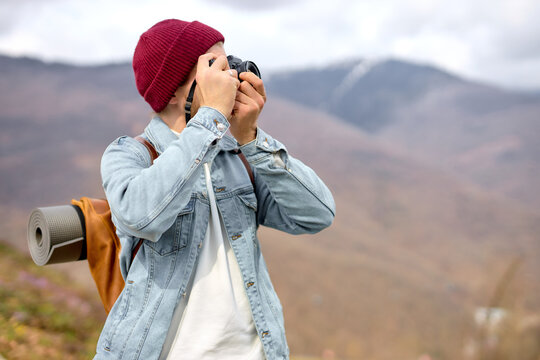 Close-up Portrait of young e traveler man taking photo of nature landscapes, in nature, at adventure alone, side view. male in denim casual jacket, in mountains