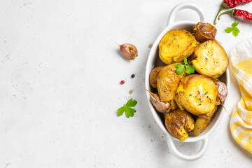 Roasted garlic smashed baked potatoes in baking dish. Top view, copy space.