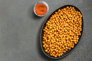 Oven roasted chickpeas in cast iron skillet on dark background. Top view, copy space.