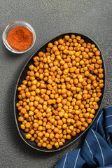Spicy oven roasted chickpeas in cast iron skillet on dark background. Top view, copy space.