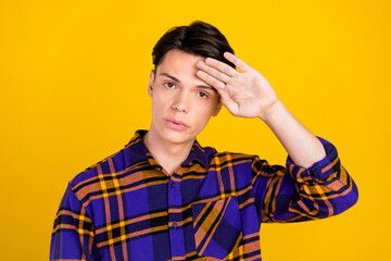 Photo of tired upset teen boy wear plaid outfit hand forehead isolated yellow color background