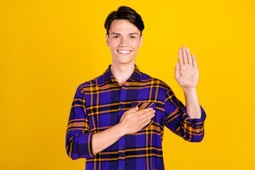 Photo of cute brunet millennial guy pray wear plaid shirt isolated on yellow color background