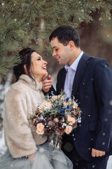 couple kissing in forest under the snow in winter
