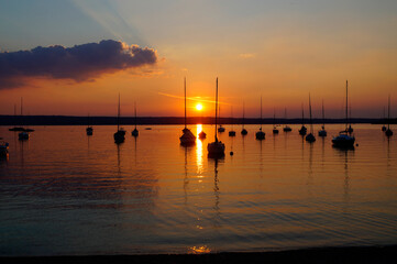 sunset at lake Ammersee in Herrsching with sailing boats resting on the water on a warm August night (Bavaria, Germany)