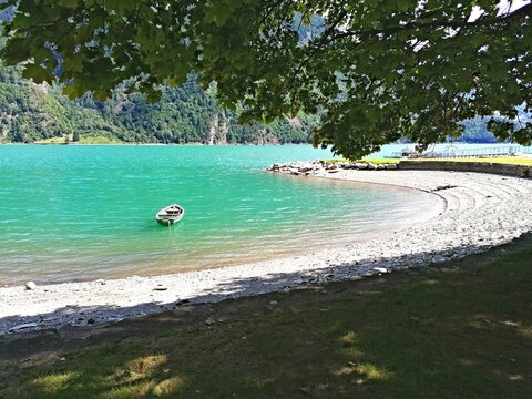 Lago di Poschiavo, in Svizzera,  barchetta sull' acqua  dai mille colori di un lago alpino.