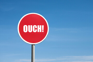 Ouch sign in a round red frame against a blue sky