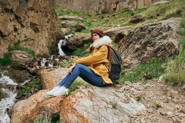 Naklejka na ściany i meble woman in yellow jacket hiking in the mountains travel adventure