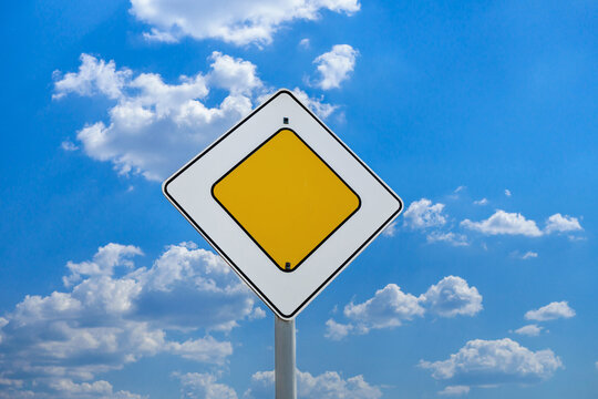 International road sign 'Main road' or 'Priority road' against a blue and slightly cloudy sky