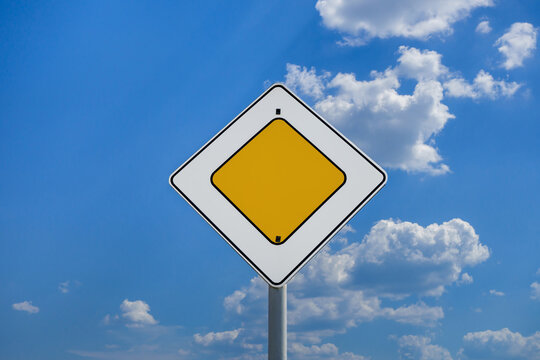 International road sign 'Priority road' or 'Main road' against a blue and slightly cloudy sky