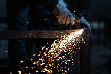 Man working on iron with grinder. Man at work. Sparkles and fire from grinder cutting. Grinder. Worker.