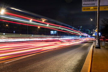 Fototapeta na wymiar night landscape with a freeway and fast moving cars leaving a solid trail 