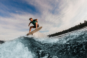 great view of man flying in the air on wakesurf over splashing wave