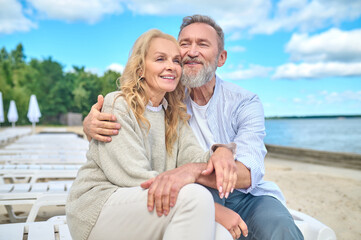 Smiling man and woman sitting on sea beach