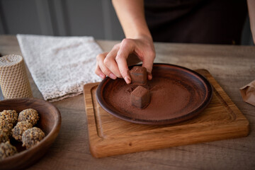 Naked women's Hands  keep chocolate candy. Brown dish with truffles. Copy space. Close-up.