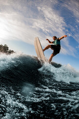 Sporting energy wakeboarder performs various extreme tricks on high splashing river wave