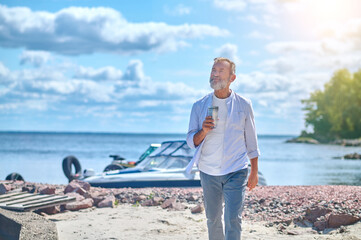Mature man walking on seashore in good mood