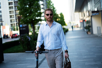 Young stylish businessman with e-scooter. Portrait of handsome man outdoors.