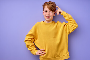 Portrait of pensive teen boy isolated on purple background. Thoughtful teenager holding hand on...