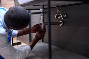 Handsome Hardworking Plumber Installing The Sink In Bathroom Close-up Photo, Cropped Black Man. Guy...