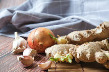 Ginger root, onion and garlic with wooden texture background