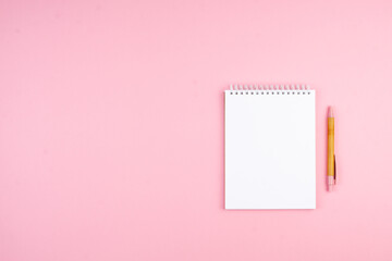 Notepad and pen on pink background. Christmas Planning Concept for 2022.