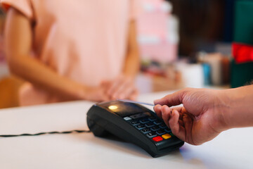 Close-up view of unrecognizable male customer paying with NFC technology by credit card contactless...
