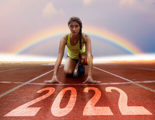 2022 New Year celebration - Racing lane with young female athlete at starting block under a rainbow