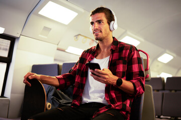 Young man listening to music while traveling by a train. Handsome young man traveling by a train..