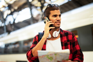 Happy young man waiting for the train. Beautiful smiling man with city map in subway..