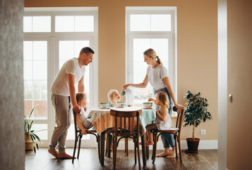 a young family has breakfast on a weekend at home in the kitchen together