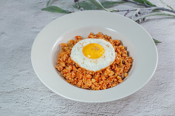 Korean food kimchi fried rice dish with fried egg on white plate