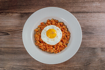 Korean food kimchi fried rice dish with fried egg on white plate